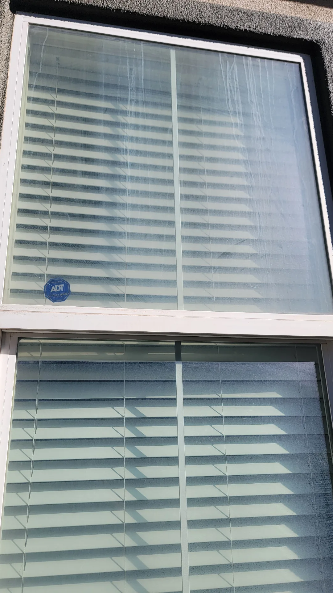 Residential window with hard water drip streaks and mineral staining before restoration
