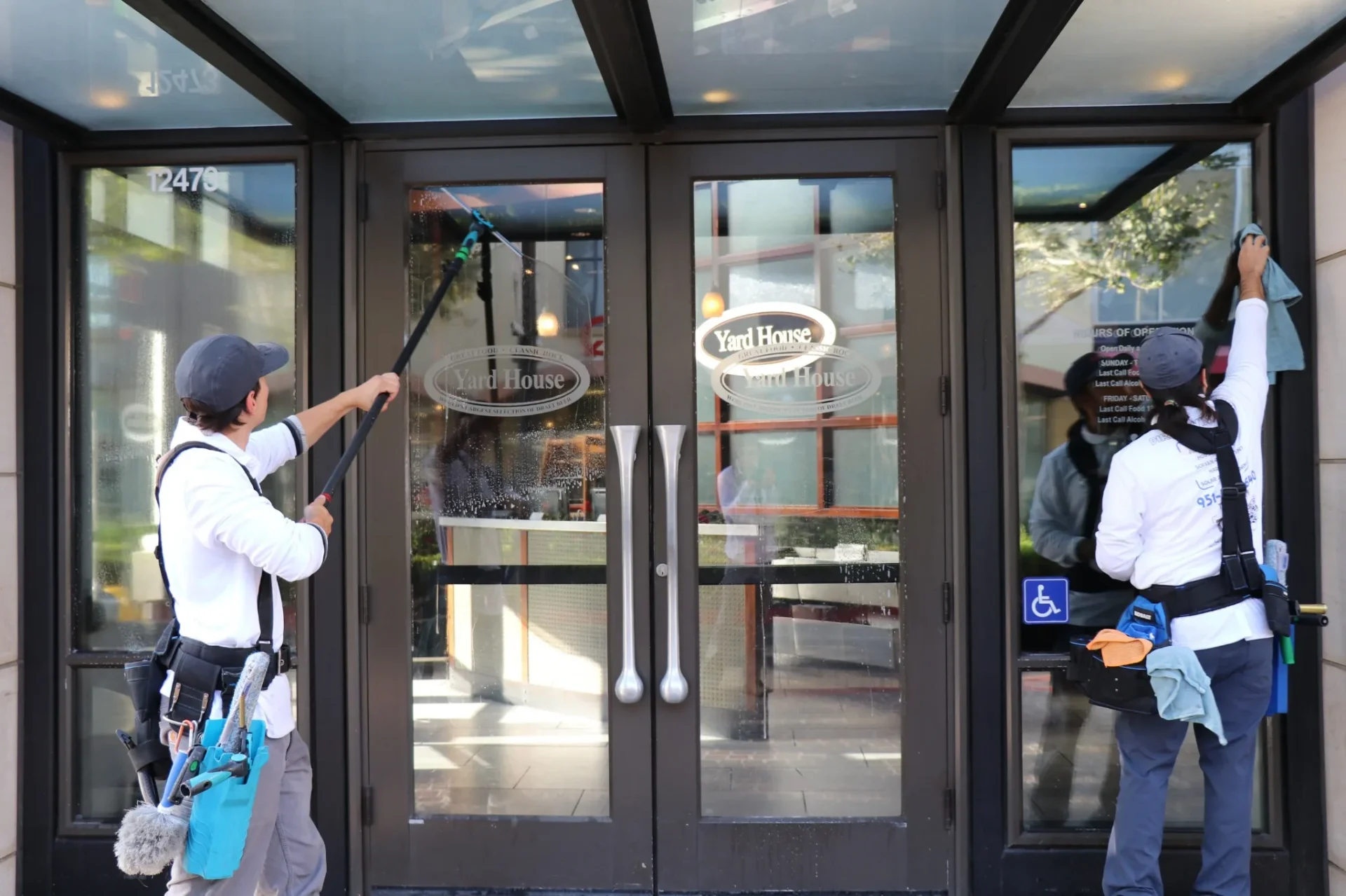 Transparent Solutions crew cleaning glass storefront doors at a commercial property