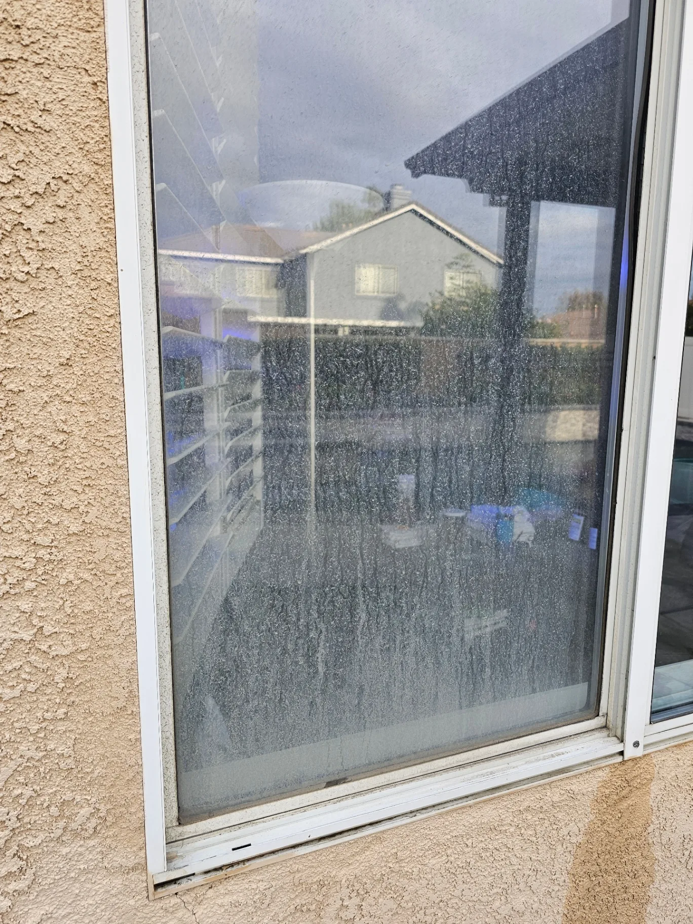 Sliding glass door coated in dust and spots before Transparent Solutions window cleaning