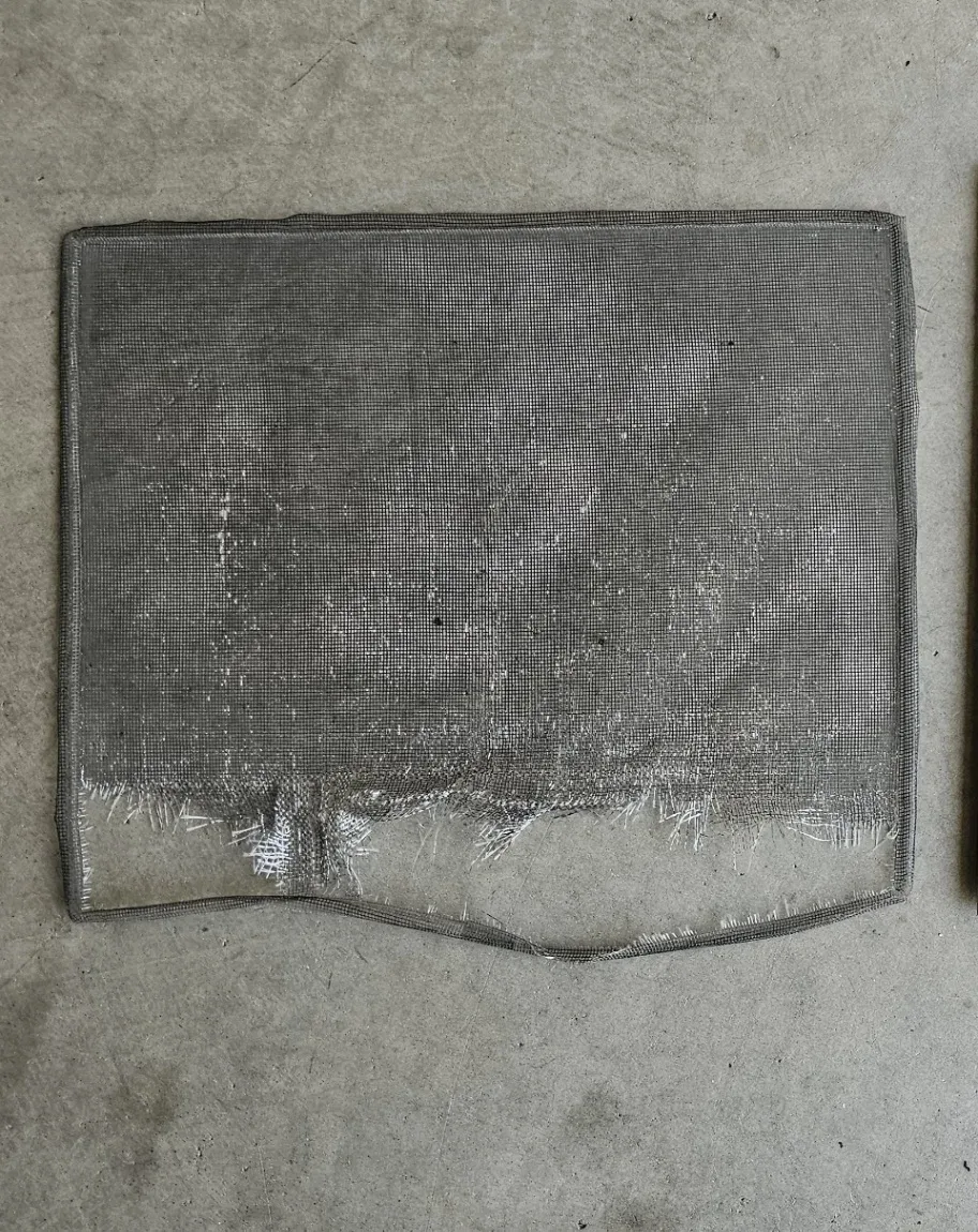 Torn and damaged window screen with shredded mesh before professional screen replacement