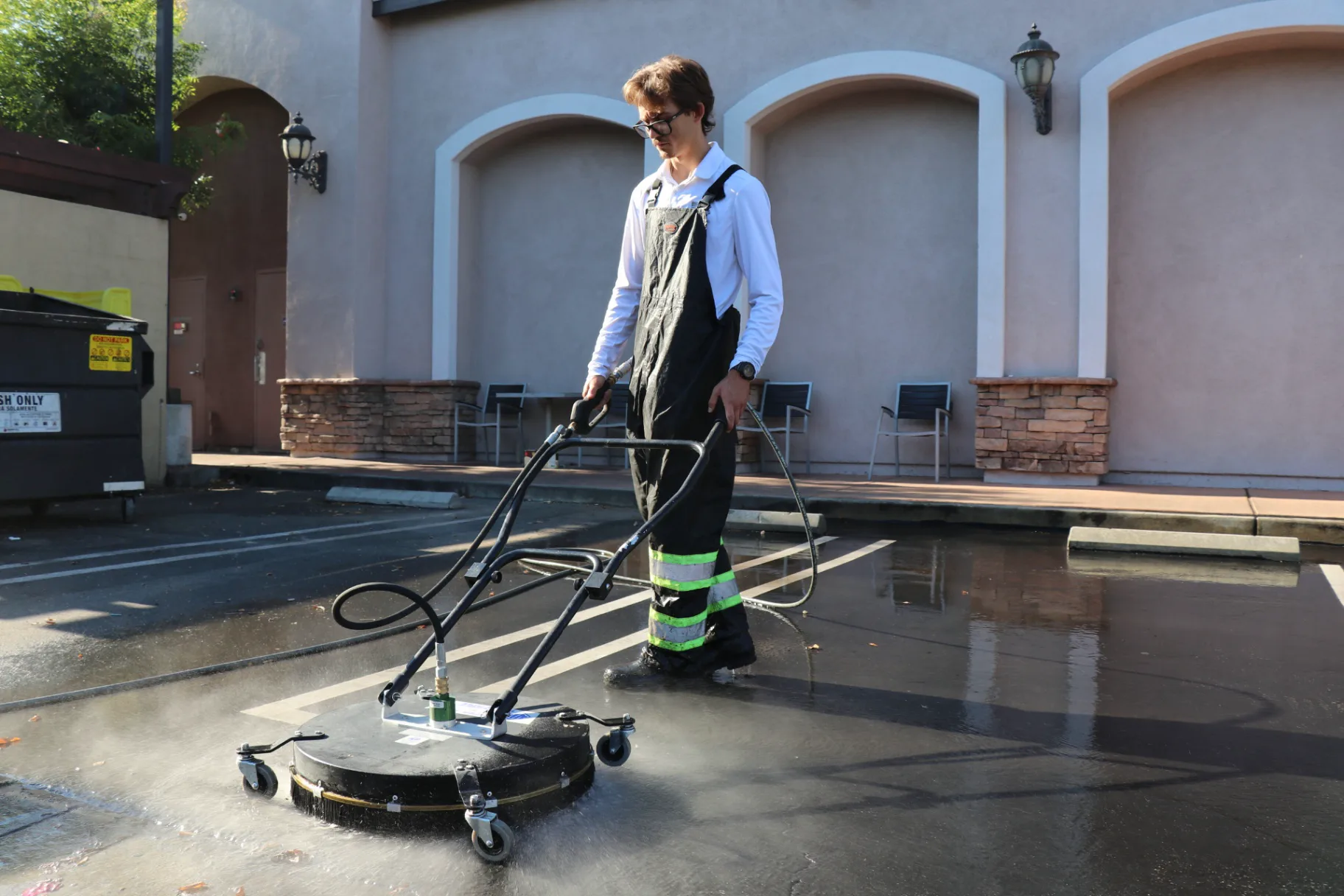 Technician surface cleaning a retail center sidewalk with a commercial flat surface cleaner