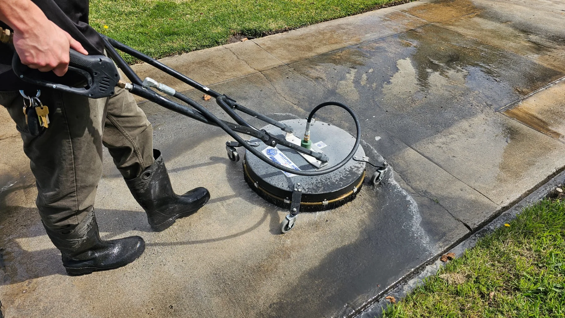 Transparent Solutions technician running a surface cleaner on a concrete driveway