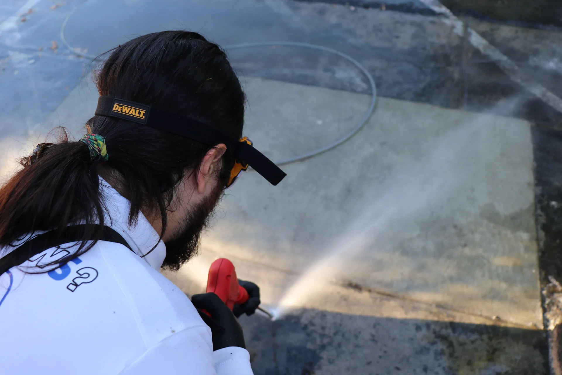 Close-up of a technician spot-cleaning commercial concrete with a pressure washing wand