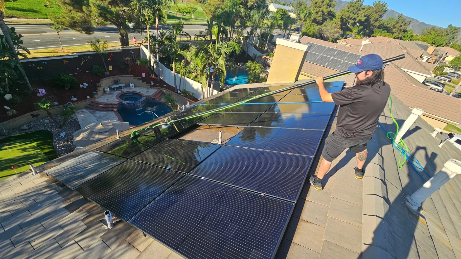 Transparent Solutions technician using a water-fed pole to clean roof-mounted solar panels