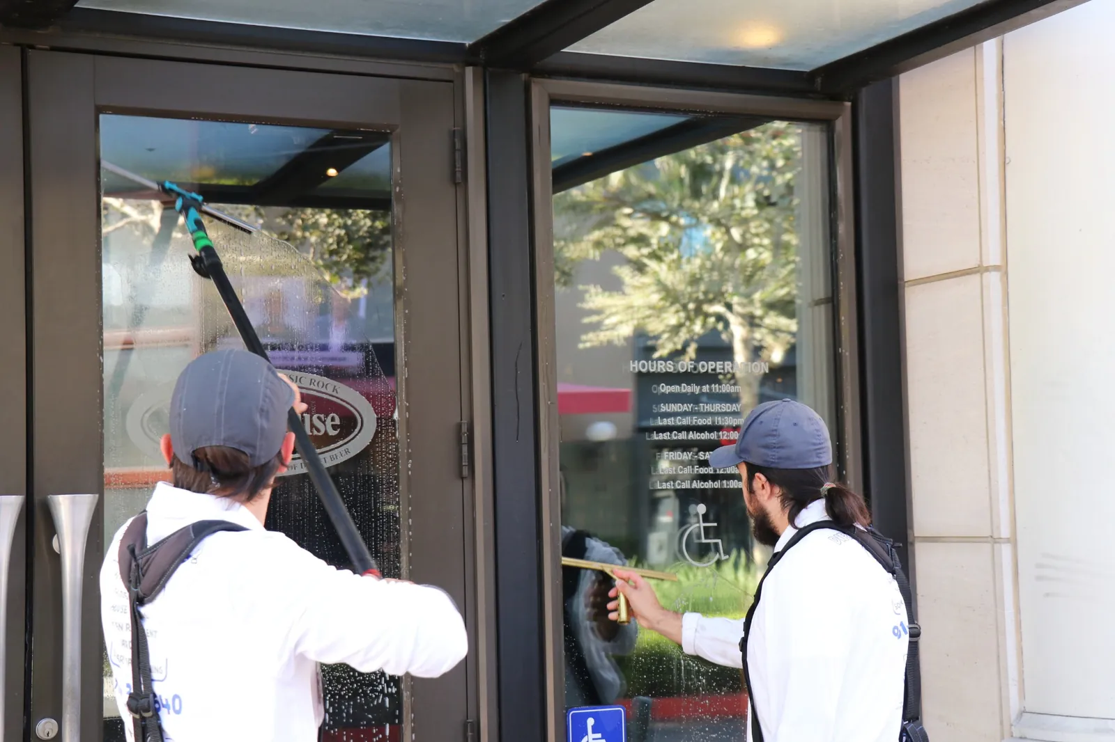 Two Transparent Solutions technicians detailing commercial storefront windows with a water-fed pole and squeegee