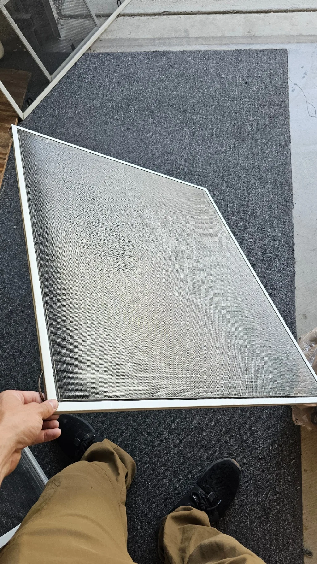 Worn and dirty window screen mesh held up to the sun before Transparent Solutions screen replacement