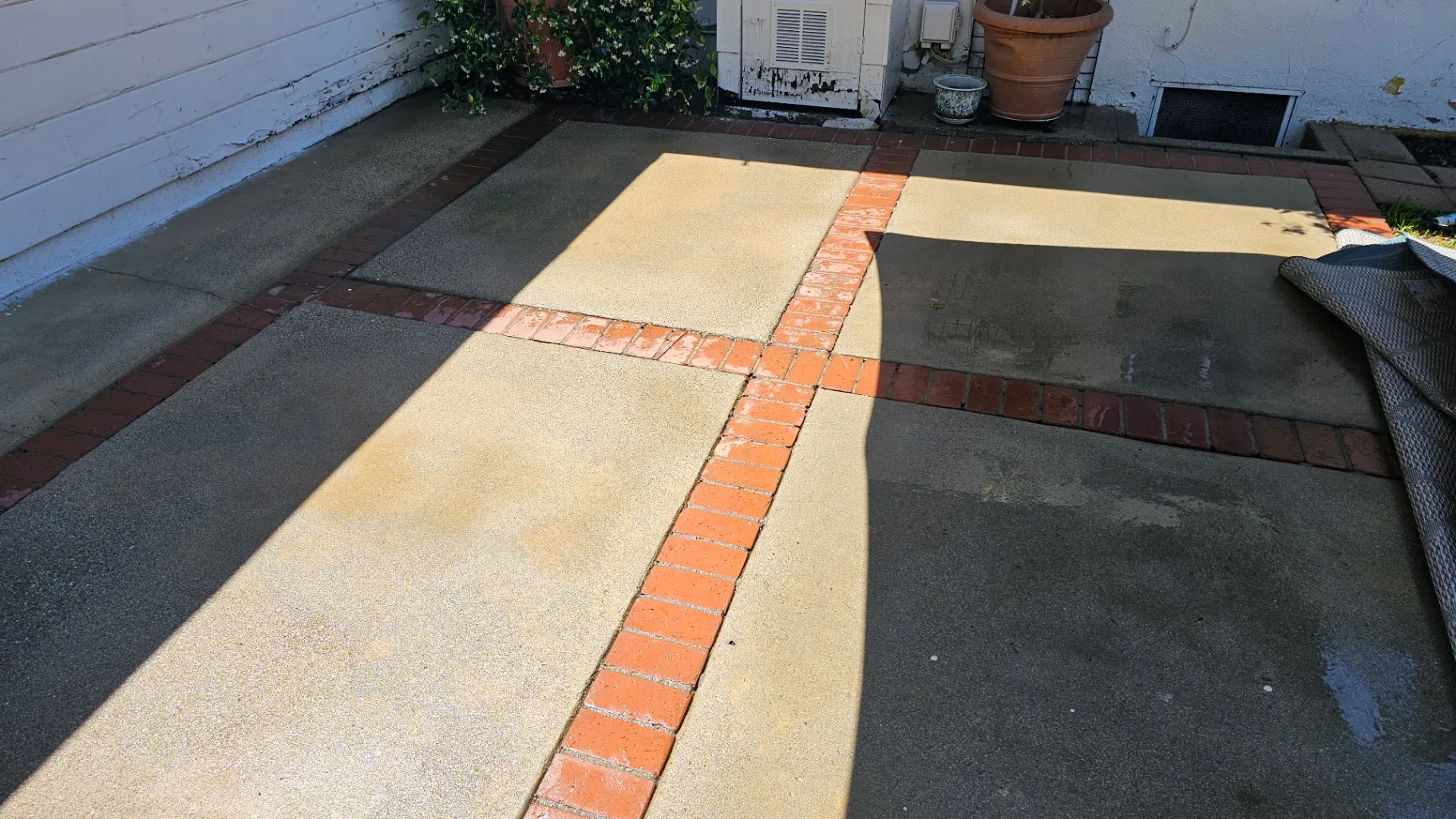 Same backyard patio with bright clean concrete after Transparent Solutions pressure washing