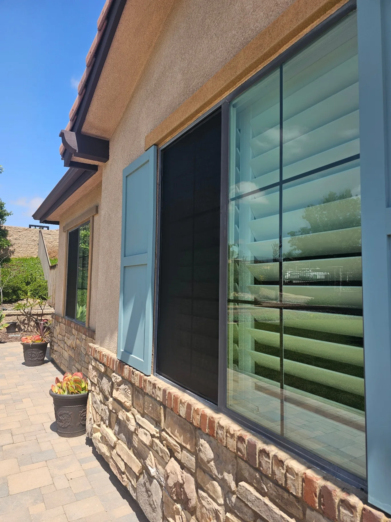 Angled view of freshly replaced patio door and window screens on a residential home